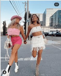 two women are walking down the street holding hands and wearing matching outfits with high heeled boots