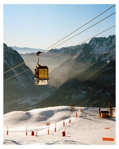 a ski lift is above the snow covered mountain range, with mountains in the background