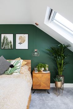 a bedroom with green walls and pictures on the wall above it, along with plants