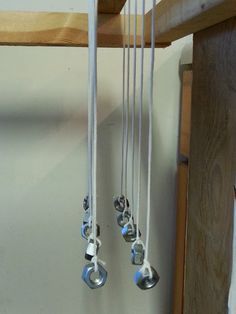 several metal bells hanging from a wooden shelf