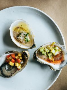 three oysters on a white plate with various toppings