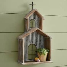 a small wooden house shaped shelf with plants on the ledge and a potted plant in it