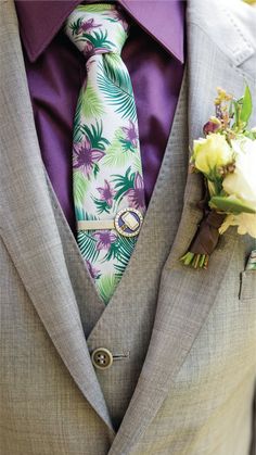 a man in a suit with a purple tie and boutonniere on his lapel