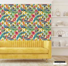 a yellow couch sitting in front of a colorful wallpaper