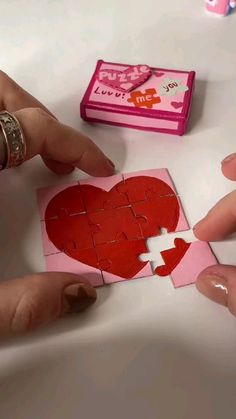 someone is cutting out a heart from a piece of pink paper with a hole in the middle