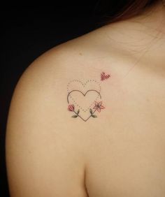 a woman's back shoulder with a heart and flowers tattoo on the left side