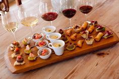 a wooden table topped with wine glasses filled with food