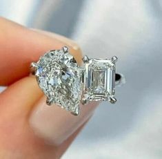 a woman's hand holding an engagement ring with three stone diamonds on it,