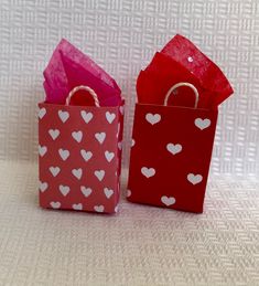 two small red and pink bags with hearts on them are sitting side by side in front of each other