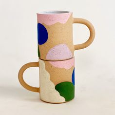 two coffee mugs sitting side by side on top of each other with different designs