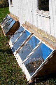 an open window on the side of a building with grass in front of it and other windows