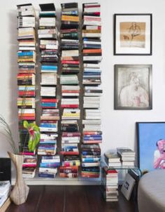 a book shelf filled with lots of books next to a bed and pictures on the wall