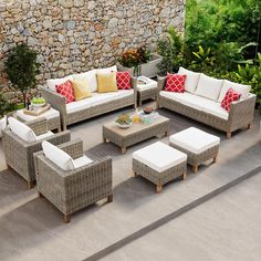 an outdoor living room with wicker furniture and stone wall behind the couches, coffee table and stools