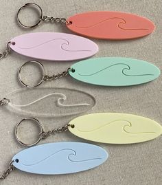 four key chains with different colors and shapes on them, one is shaped like a wave