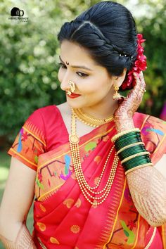 a woman in a red sari with gold jewelry on her neck and hands behind her head