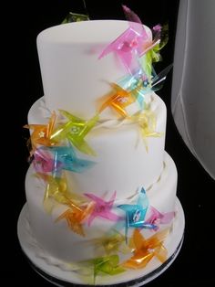 a multi - layered white cake with colorful stars on the top and bottom tiers