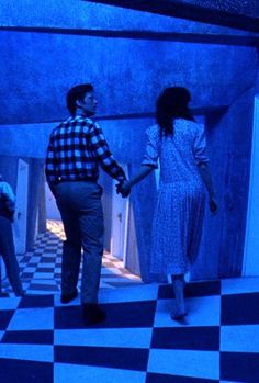 a man and woman holding hands in a room with checkered floor