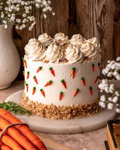 a carrot cake with frosting and sprinkles sits on a plate next to flowers