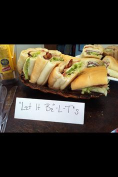 a table topped with lots of sandwiches next to a sign