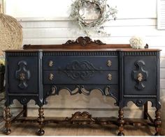 an ornately decorated sideboard with two drawers and one drawer on the top, in front of a white wall