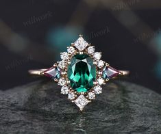 an emerald colored stone surrounded by white and pink diamonds on top of a black rock