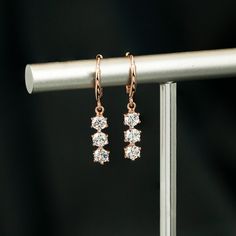 ✥ Elevate your elegance with our Round Cut Three Stone Diamond Dangle Earrings for Women. These exquisite earrings feature a trio of sparkling round cut diamonds elegantly arranged in a dangle setting, adding glamour and sophistication to any look. Crafted from premium materials for durability and lasting shine, they are perfect for special occasions or everyday wear. The dangle design creates movement and catches the light, ensuring attention to detail. A luxurious gift choice symbolizing timel Wedding Three Stone Earrings In Fine Jewelry, Wedding Three Stone Fine Jewelry Earrings, Elegant Three Stone Wedding Earrings, Wedding Three Stone Fine Earrings, Elegant Three-stone Wedding Earrings, Formal Rose Gold Three Stone Jewelry, Three-stone Diamond Earrings For Wedding, Elegant Diamond White Three Stone Diamond Earrings, Wedding Diamond Earrings With Three Stones