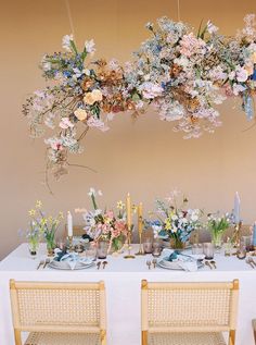 a table with flowers and candles is set up for a dinner or party in front of a wall