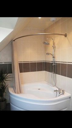 a bath tub sitting under a bathroom window next to a potted plant on the floor