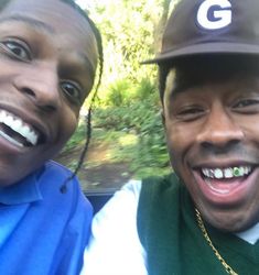 two people are taking a selfie in the back of a car with trees in the background