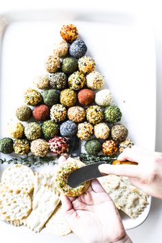 a person is cutting into a christmas tree shaped snack on a plate with crackers