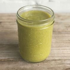 a jar filled with green liquid sitting on top of a wooden table