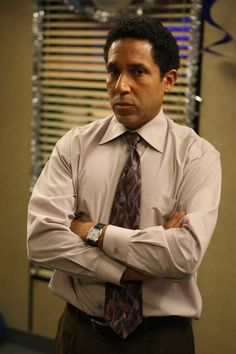 a man with his arms crossed wearing a dress shirt and tie