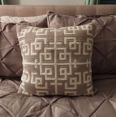 a close up of a pillow on a bed with brown sheets and pillows in the background