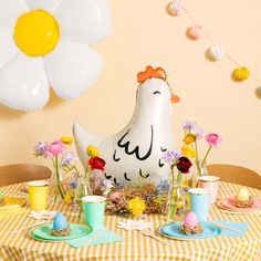 a table topped with an inflatable chicken next to plates and cups filled with food