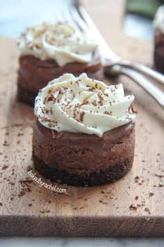 two chocolate desserts with white frosting on a cutting board next to a fork