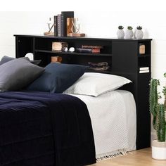 a bed with pillows and blankets on top of it next to a potted plant