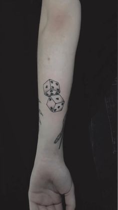 a person with a tattoo on their arm holding dices in one hand and playing cards in the other