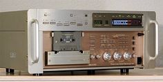 an electronic device sitting on top of a wooden table next to a wall mounted clock