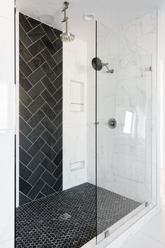 a walk in shower sitting next to a white tiled wall and floor with black tiles on the walls