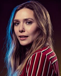 a woman with long hair wearing a red and white striped shirt looking at the camera