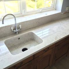 a kitchen sink sitting under a window next to a counter