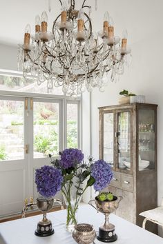 a chandelier hanging from the ceiling above a table with flowers in vases