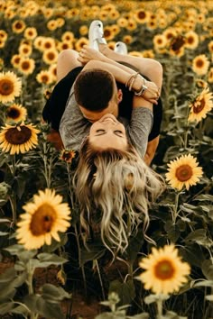 a man holding a woman in the middle of a field of sunflowers