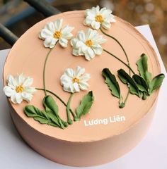 a cake decorated with white flowers and green leaves