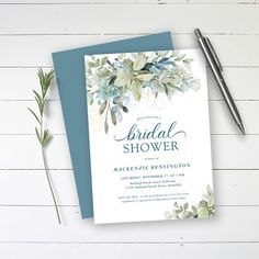 a blue and white floral bridal shower card on top of a table next to a pen