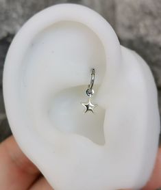 a tiny silver star charm on a white ear