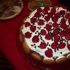 a cake with white frosting and raspberries on top sitting on a table