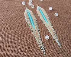 two pairs of beaded earrings laying on top of a piece of brown fabric next to some crystal beads