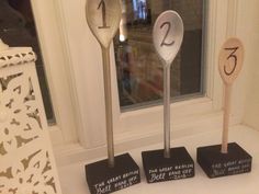 three wooden spoons with numbers on them sitting in front of a window sill