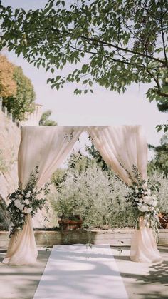 an outdoor wedding setup with white drapes and flowers